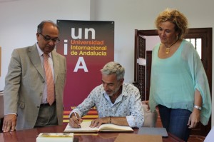 Imanol Arias firma en el libro de honor en presencia del rector y la directora de la sede de La Rábida.
