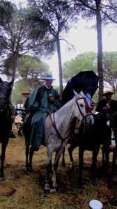 Jinetes de la Hermandad del Rocío de Lucena del Puerto protegiendose de la lluvia del camino bajo impermeables y paraguas