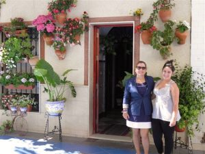 Isabel López junto a la hija de la premiada en la fachada de su vivienda.