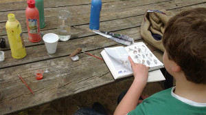 Un participante de la Escuela de Exploradores estudia las características del ave que está realizando en barro.