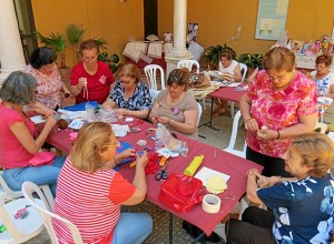 Mujeres realizando trabajos de manualidades y bolillos.