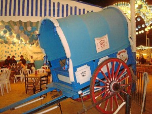 A la entrada de la caseta, un carro tradicional recibe a los onubenses. 