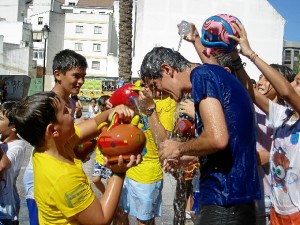 El alcalde de Galaroza, Antonio Sosa Muñiz, entre una multitud de niños con jarritos.