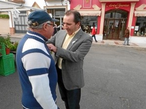 El alcalde de Almonte prende un lazo a un vecino.