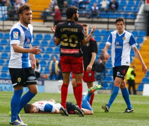 Un jugador del Hércules sobre el césped, mientras Menosse parece hablar con el árbitro. / Foto: José Navarro.