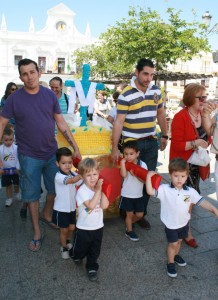 Los niños transportando una cruz pequeña por las calles de Cartaya, ayudados por sus padres.