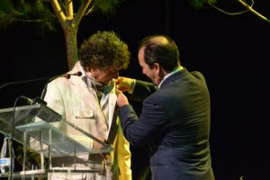 El alcalde de Almonte, José Antonio Domínguez, coloca la insignia al cronista de la Romería 2014, Jesús Quintero.