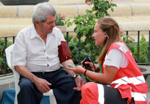 Una joven de Cruz Roja tomando la tensión a un paciente.