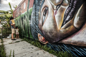 Juan Luis enseña a dos niñas la flora y la fauna de la selva a través de murales.