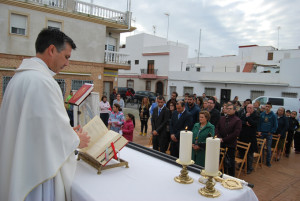 El cura oficia la misa mientras autoridades y vecinos la siguen atentos