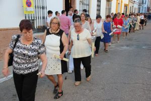 Mujeres con velas de promesas delante del paso.