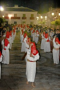 Nazarenos descalzaos con cadenas y portando cruces de madera.