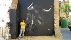 El artista urbano, Víctor Romero 'Konestilo', junto a uno de sus trabajos junto a la Plaza de Toros de la Merced.