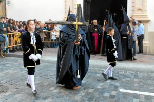 Los nazarenos visten túnica, capa, morrión y escapulario azul marino.