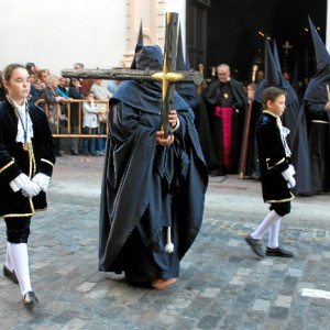 Los nazarenos visten túnica, capa, morrión y escapulario azul marino.