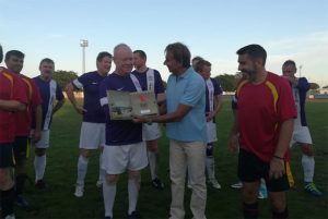 El concejal de Deportes de Punta Umbría, Juan José Iglesias, entrega un obsequio al equipo inglés de veteranos.