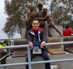 Juan Manuel Garrido Anes, con el libro ‘No quiero verte llorar. Cuando Huelva resucitó al Decano’ del que es autor, delante del monumento.