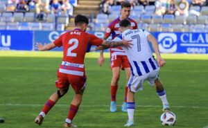 Iago Díaz protege la pelota ante el acoso de Raúl. / Foto: @recreoficial.