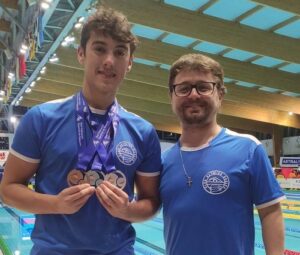 Samuel Gómez -izquierda- posa junto al técnico Federico Corteggiano con las medallas logradas en el Campeonato de España. / Foto: @CNHUELVA.